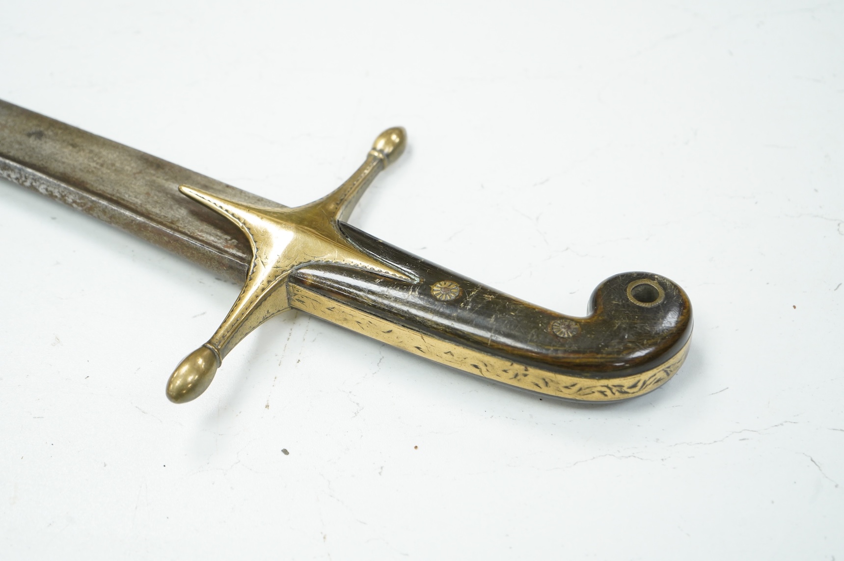 An Ottoman sword kilij with rounded back edge, traces of gold cartouche to the blade, brass cross piece, and two-piece horn grip, blade approximately 76cm